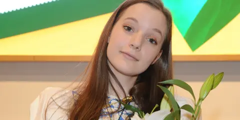 Sanah z bukietem białych lilii, uśmiechnięta, jakby przeżywała najlepszy dzień w moim życiu.