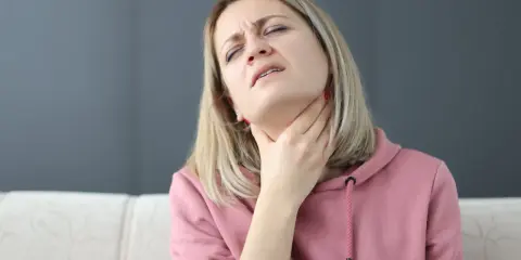 Kobieta z bólem szyi, próbująca ćwiczenia na porażenie fałdu głosowego.