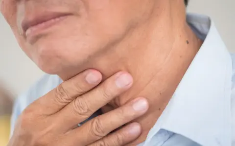 Dłoń dotyka szyi, gdzie znajdują się struny głosowe. Człowiek ma dwie struny głosowe.