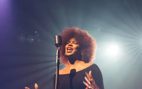 Kobieta z burzą afro włosów śpiewa do mikrofonu, jej głos jest niczym unchained melody, wolny i pełen emocji.