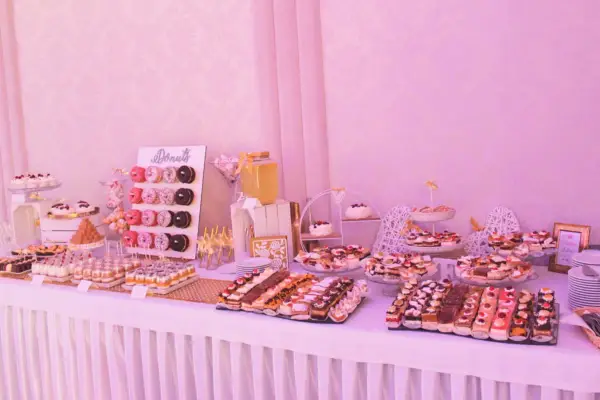 Słodki stół weselny dla 80 osób: mnóstwo ciast, babeczek i donutów.